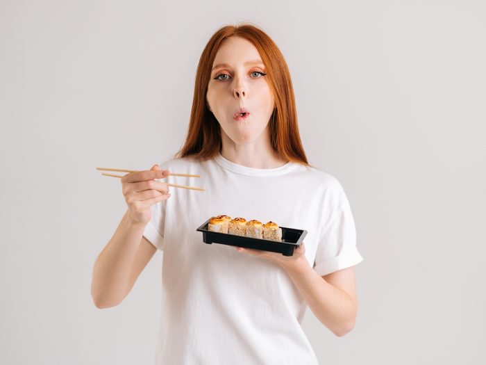 Studio,portrait,of,beautiful,young,woman,eating,delicious,sushi,rolls