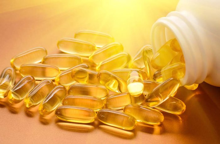 Gélules de vitamines D illuminées par un rayon de soleil.