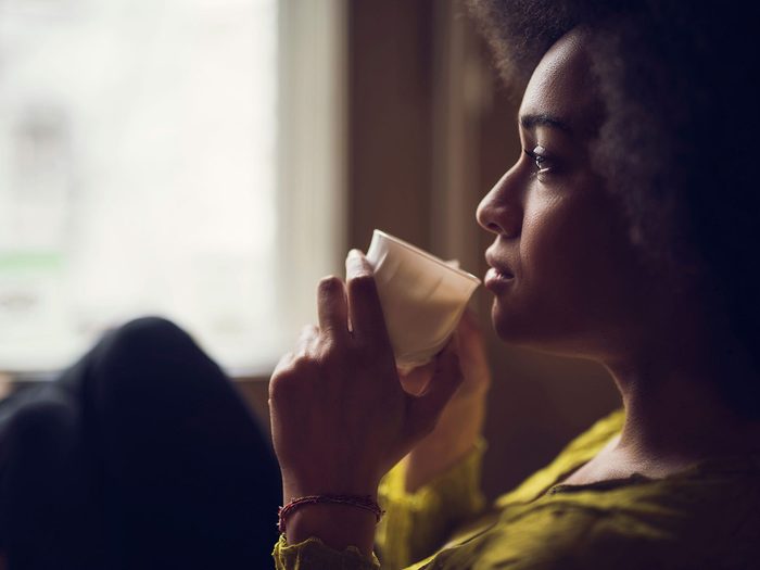 Une fille assise qui boit une tasse de café ou de thé.