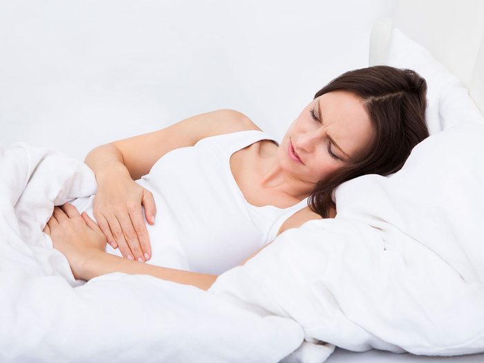 Infertilité: une femme souffre de ses règles menstruelles dans son lit.