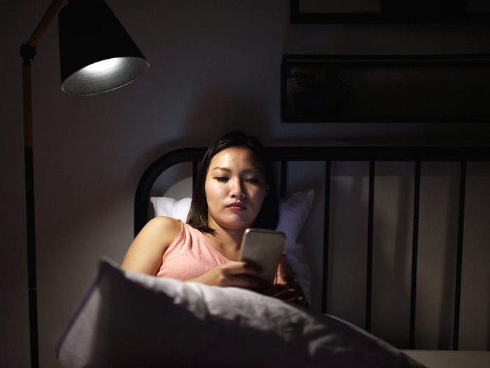Dépression: une femme regarde son téléphone au lit.