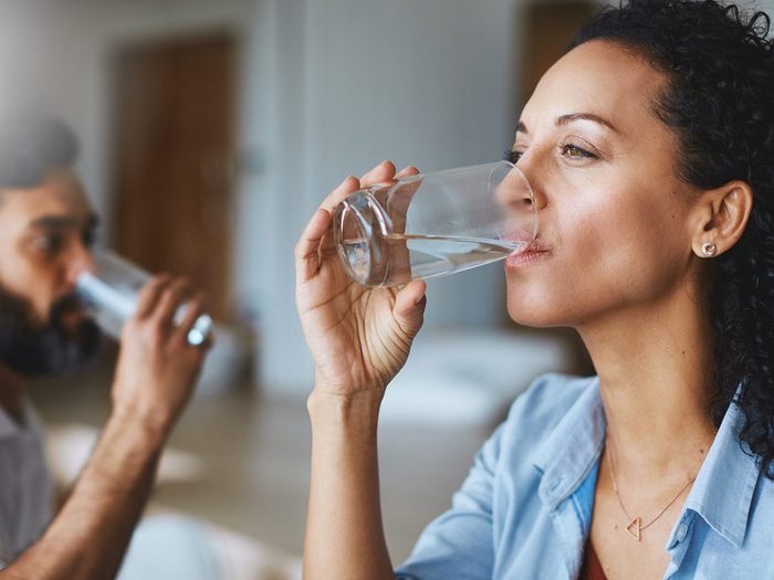Une femme boit un verre d'eau.