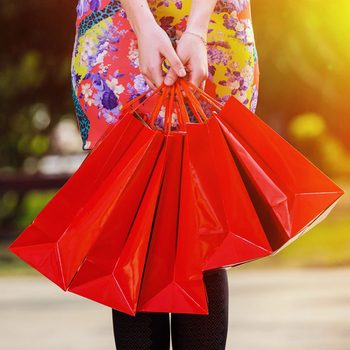 Une femme tient plusieurs sacs rouges provenant de magasins.