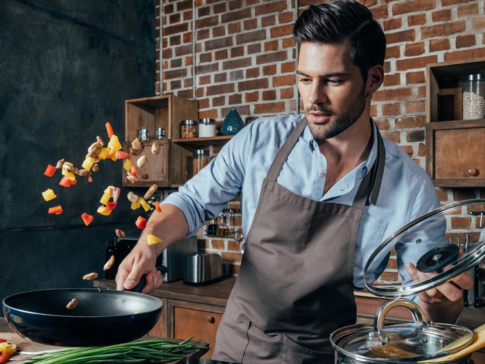 Pensive,young,man,with,apron,frying,vegetables