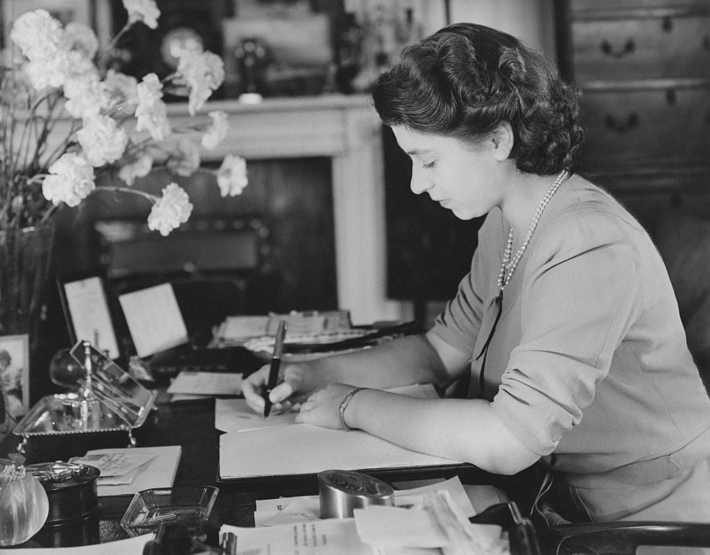 La reine Elizabeth écrit sur un cahier dans son bureau