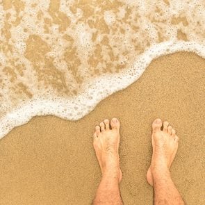 Pieds nus sur le sable au bord de la mer.
