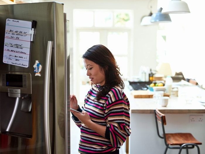 Femme d'âge moyen devant son réfrigérateur.