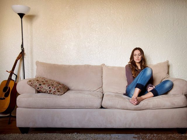 Upset Woman Sitting On Sofa At Home