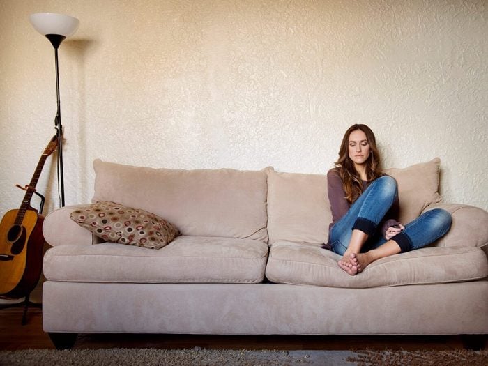 Upset Woman Sitting On Sofa At Home