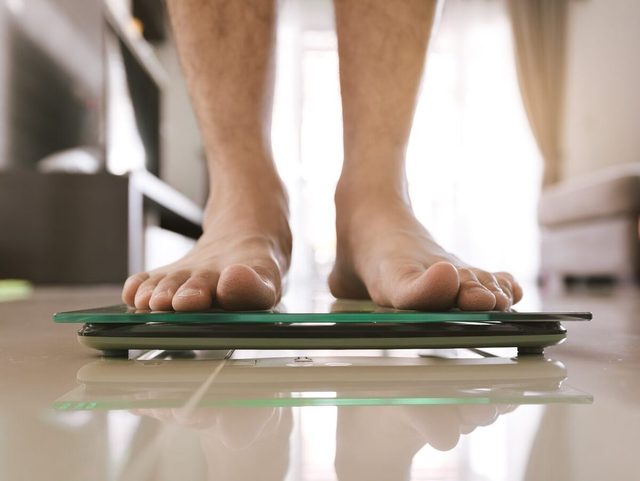 Low Section Of Man Standing On Weight Scale