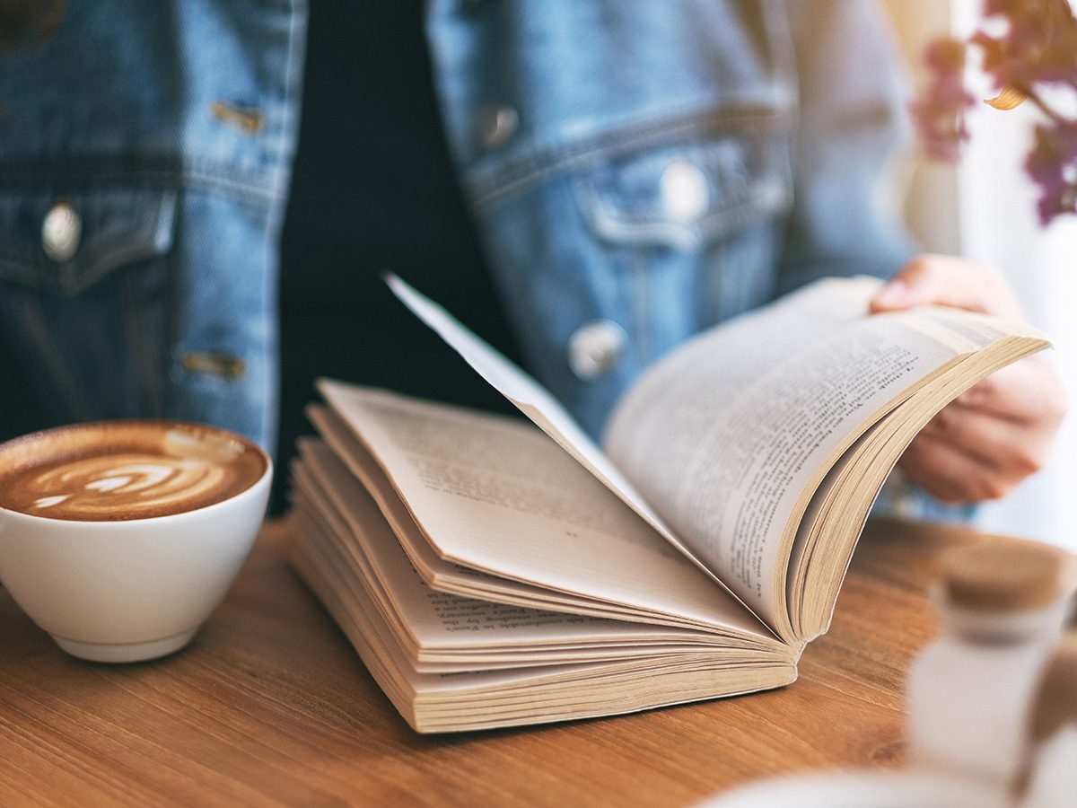 Une personne lit un livre dans un café.