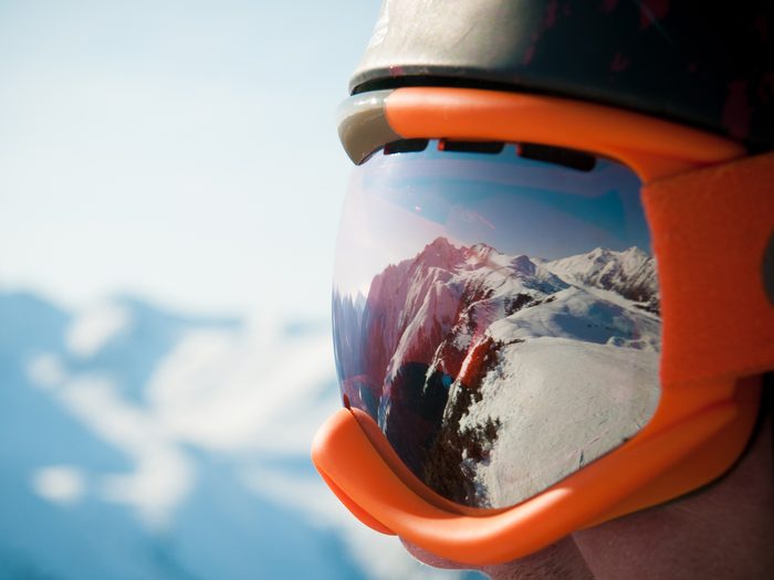 Des lunettes de ski avec le reflet d'une piste de ski.