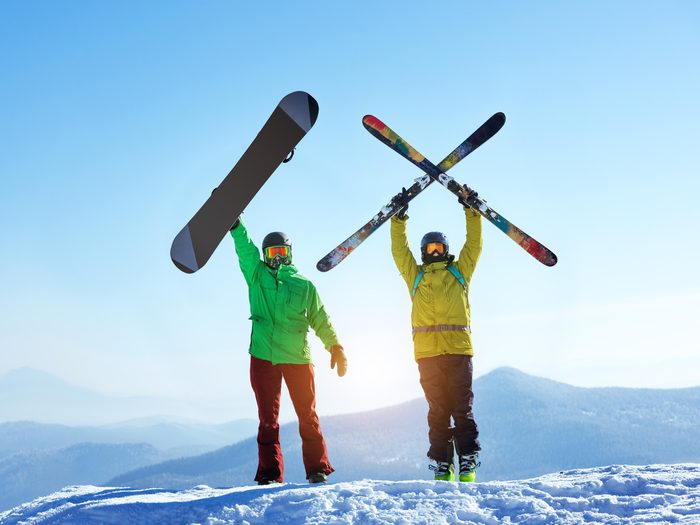 Un skieur et un snowboarder au sommet d'une piste de ski.