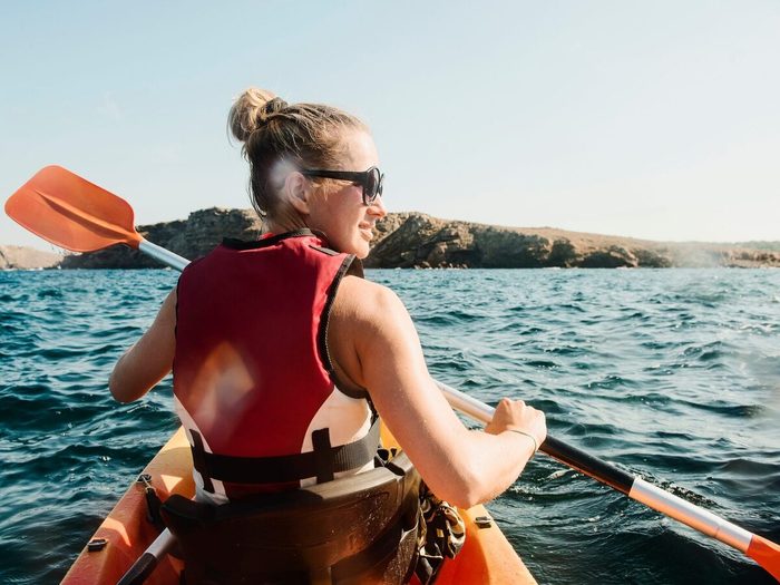 Rear View Of Mid Adult Woman Sea Kayaking, Menorca, Balearic Islands, Spain