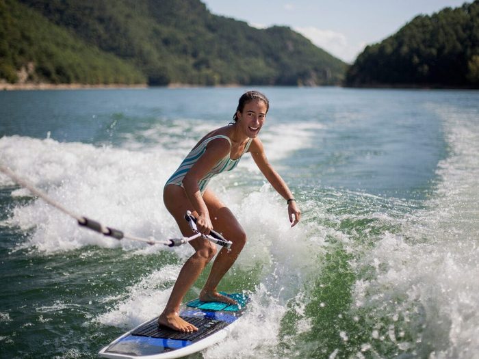 Girl Surfing In Lake Against Mountains