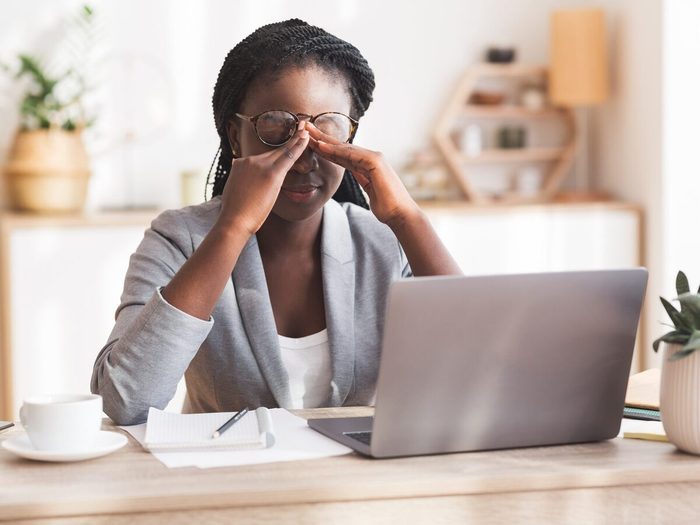 Overworked Black Businesswoman Massaging Nosebridge At Workplace Having Eyesight Problem