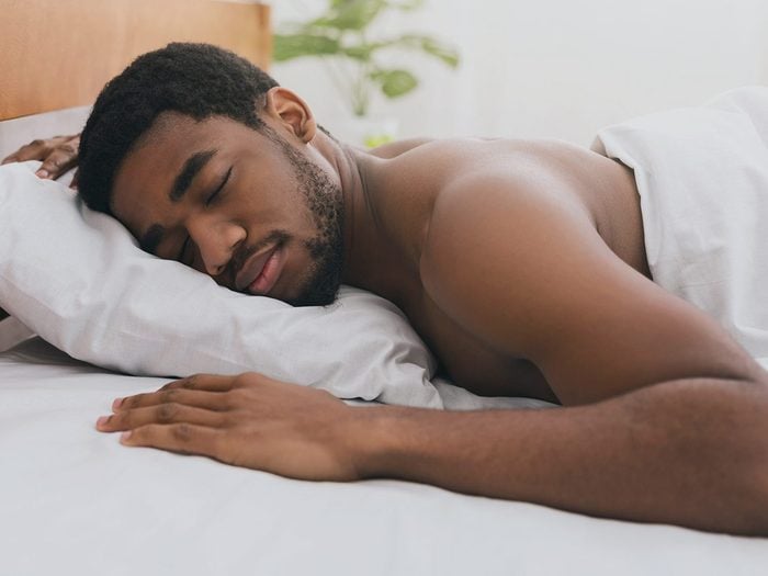 Dormir nu: un homme dort dans un lit