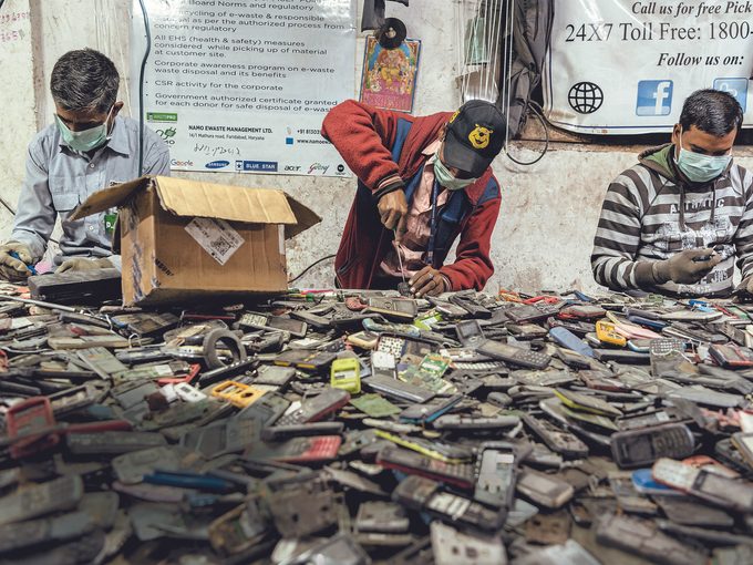 Des ouvriers récupèrent les pièces de vieux téléphones portables.