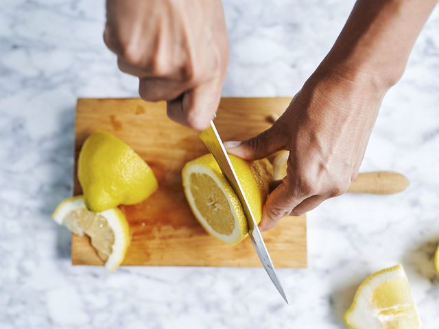 Inviter chez soi: une personne coupe un citron sur une planche  dcouper.