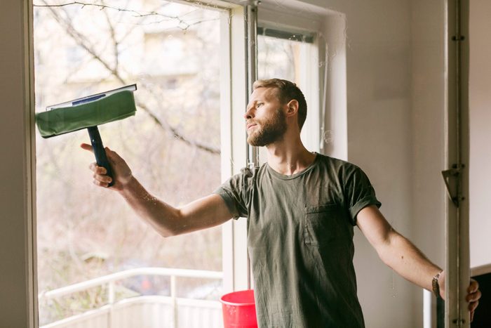 Inviter chez soi: un homme lave les vitres de ses fenêtres.