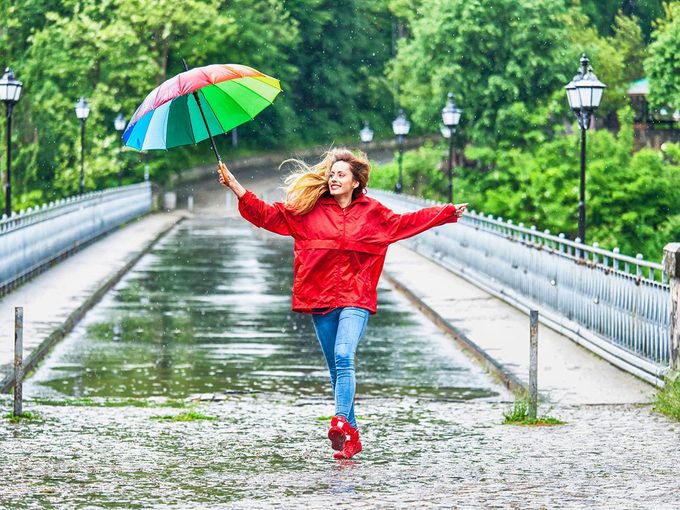 Risque de diabète: une femme marche sous la pluie, heureuse.
