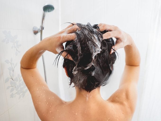 Shampooing périmé: une personne se lave les cheveux dans la douche.