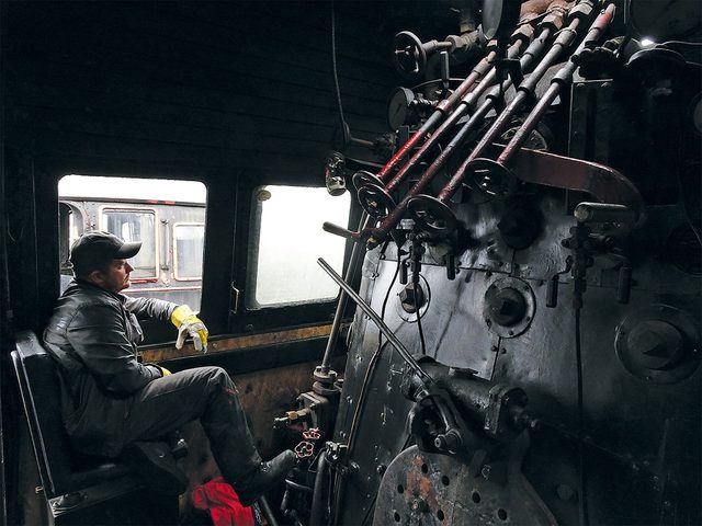 Train  vapeur: Marcin, le chauffeur, dans la cabine de la locomotive, entour dun ventail de leviers et de poignes.