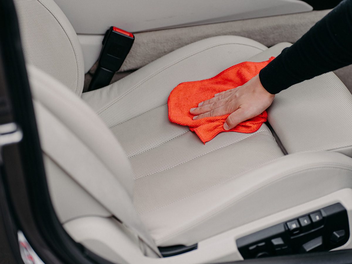 Nettoyer intérieur voiture: une personne passe un chiffon sur un siège d'auto.