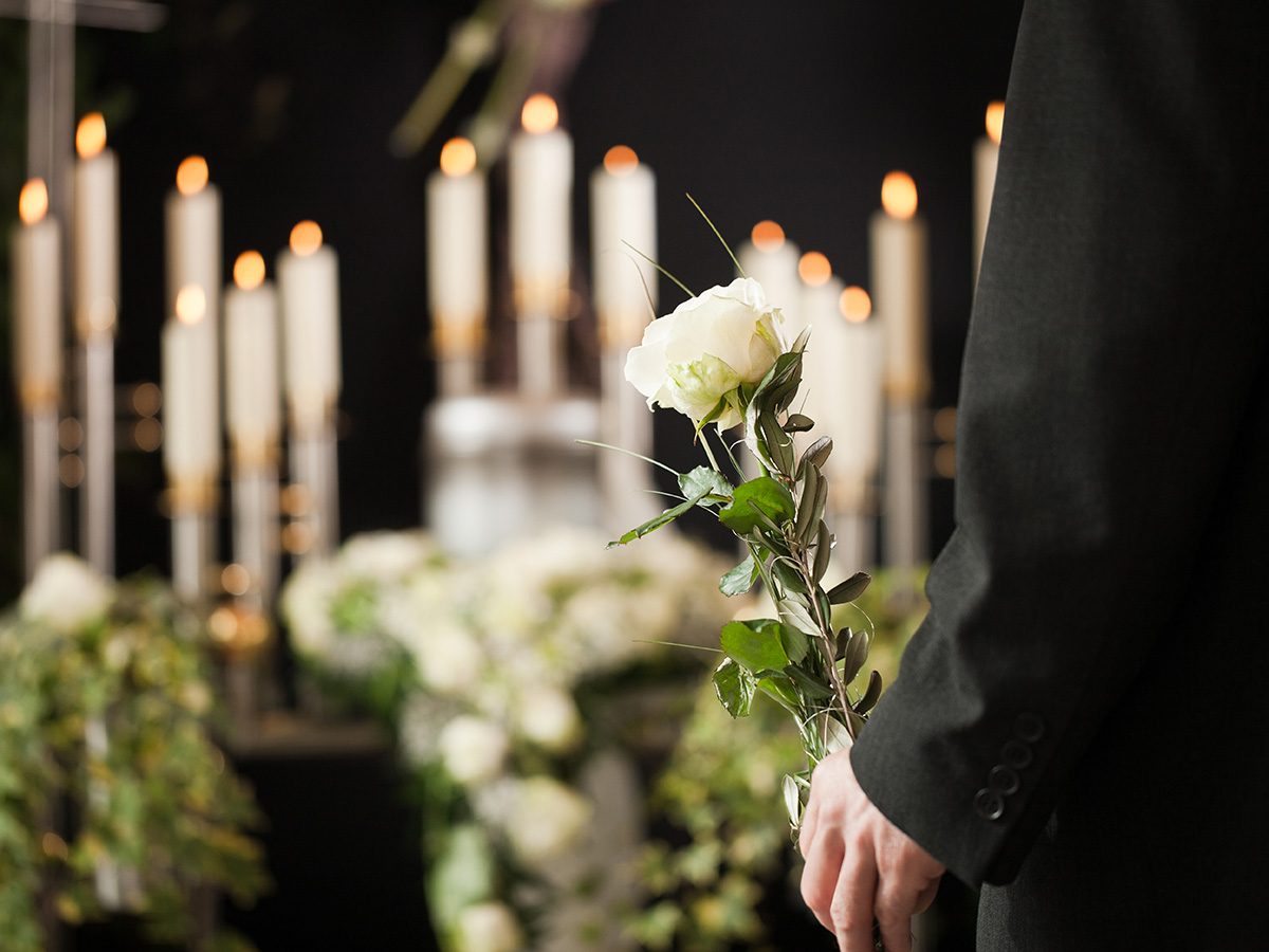 Industrie funéraire: un homme tient une fleur devant des bougies.